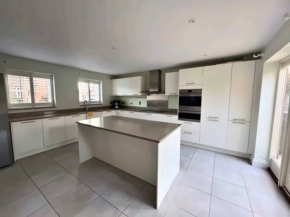 Cream kitchen with a central island, range extractor and double ovens, photographed before removal.
