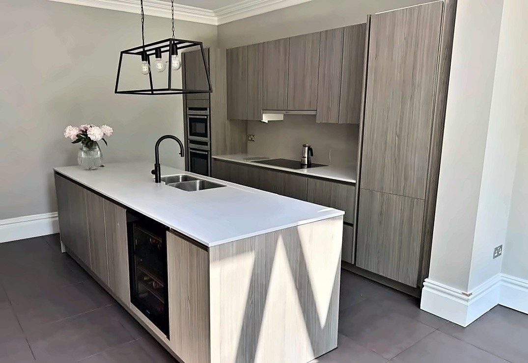 Grey woodgrain island kitchen with a white quartz worktop and integrated wine cooler.